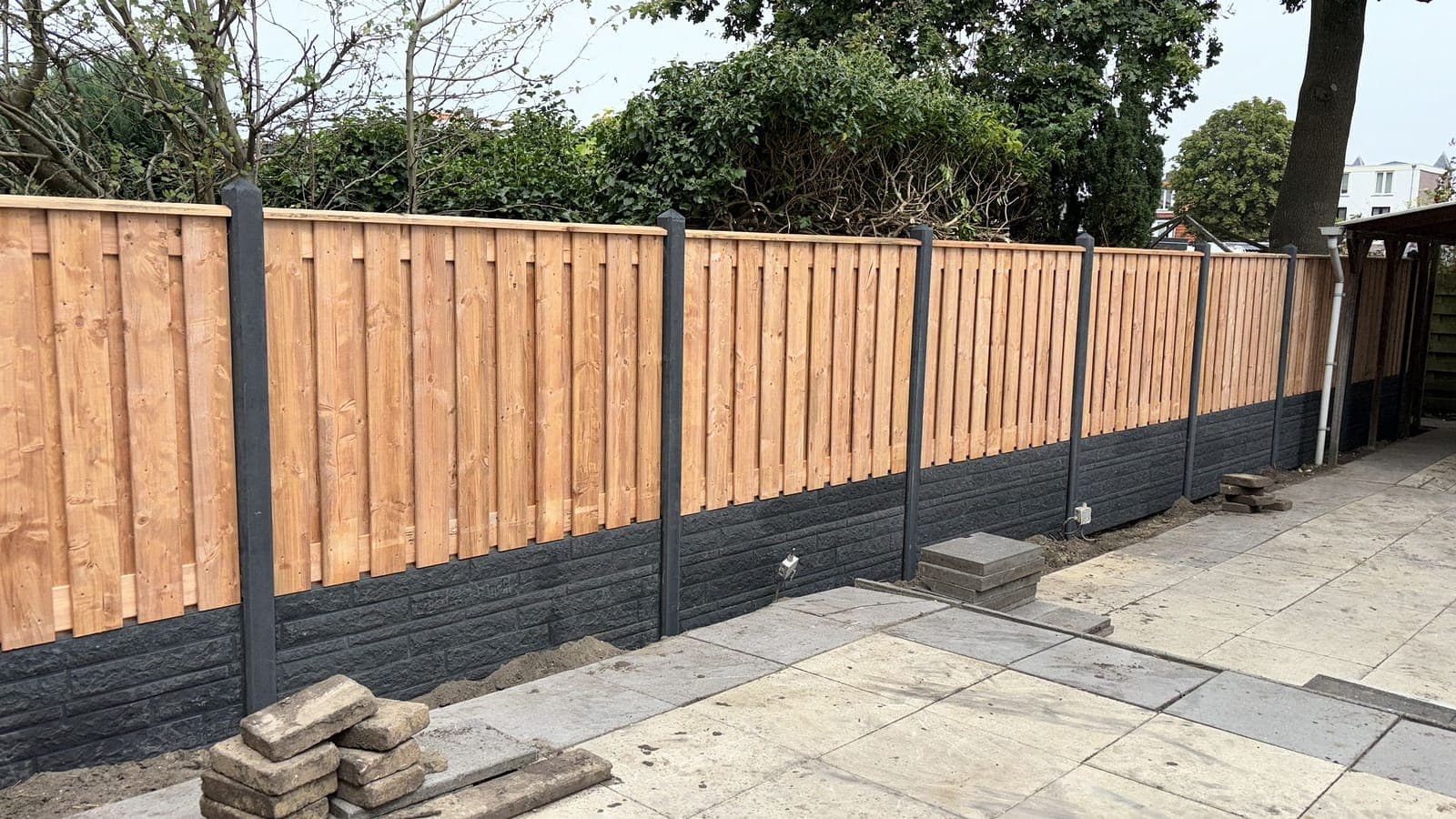 Schutting met betonnen palen en houten bekleding